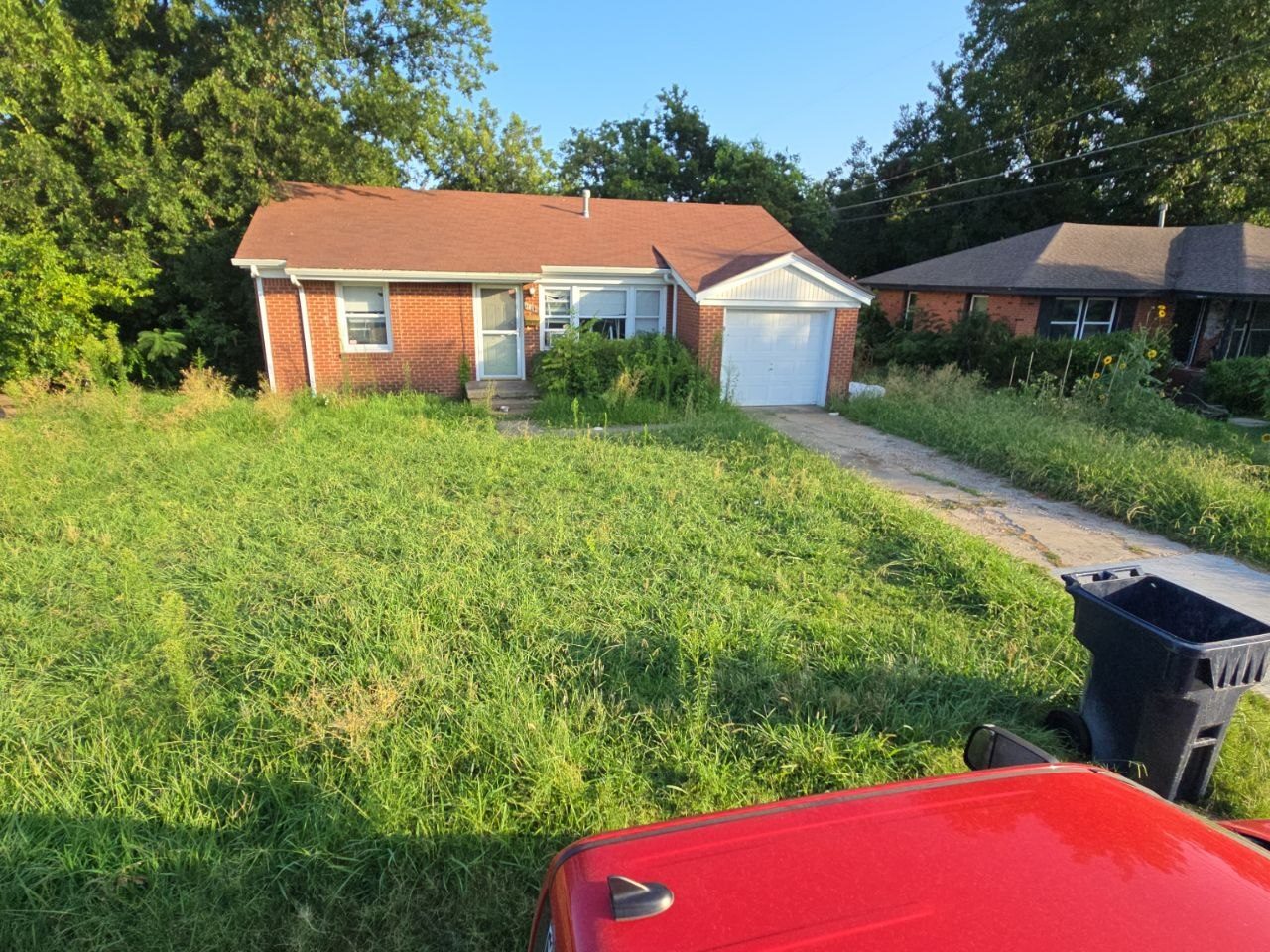 Before: overgrown front yard and driveway area before Perry Landscaping cleanup